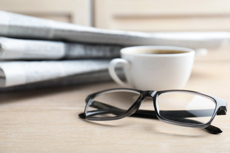 Stack of newspapers, coffee and glasses on wooden table, closeupの写真素材