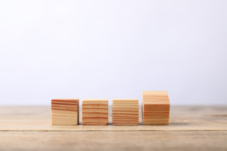 Blank cubes on wooden table against light background, space for textの写真素材
