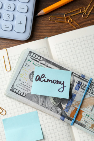 Note with word Alimony, money, notebook, pencil, clips and calculator on wooden table, flat layの写真素材