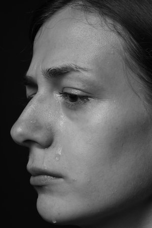 Sad woman crying on dark background, closeup. Black and white effectの写真素材