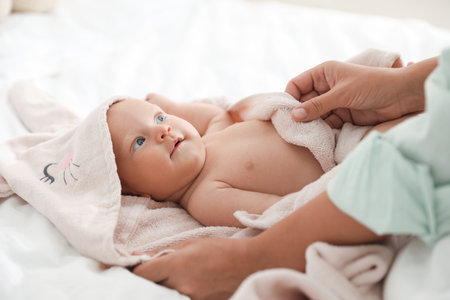Mother covering her baby with towel after bathing on bed, closeupの写真素材