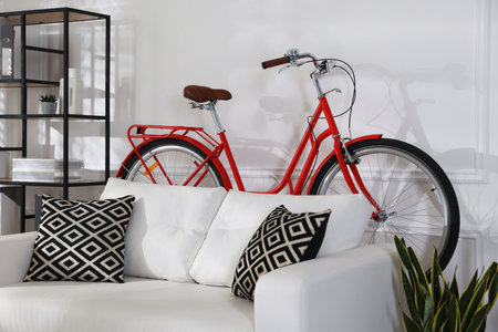 Red bicycle, sofa and houseplant in roomの写真素材