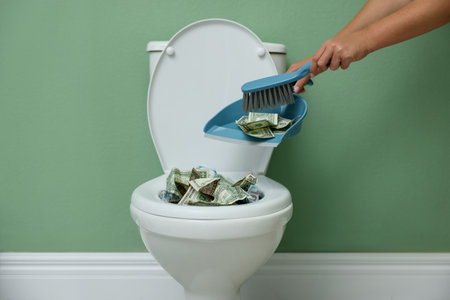 Woman throwing dollar banknotes from dustpan into toilet bowl indoors, closeupの写真素材