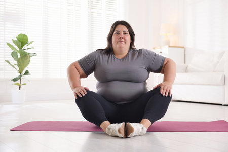 Woman in sportswear training on yoga mat at homeの写真素材