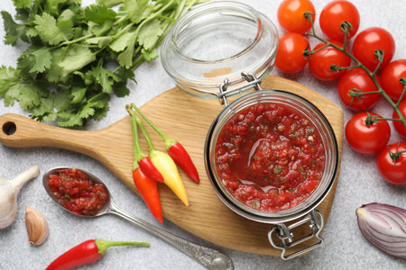 Tasty salsa sauce in jar and ingredients on light table, flat layの写真素材