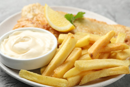 British Traditional Fish and chips with sauce, lemon and parsley on gray table, closeupの写真素材