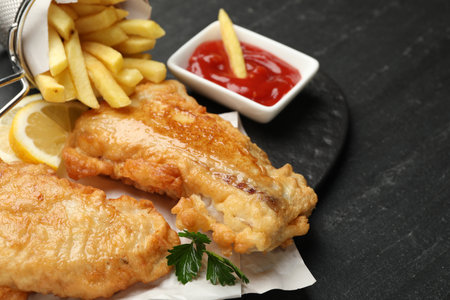 British Traditional Fish and chips with sauce and lemon on dark textured table, closeupの写真素材
