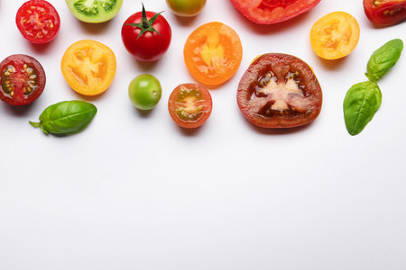 Ripe colorful tomatoes and basil on white background, flat lay. Space for textの写真素材