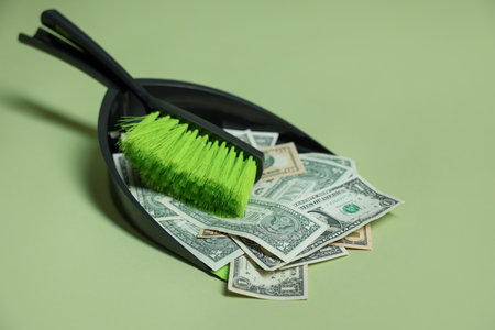 Dollar banknotes, dustpan and broom on green background, closeupの写真素材