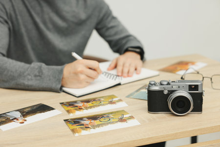 Professional photographer working at wooden table in studio, focus on vintage camera and photosの写真素材