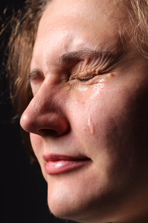 Sad woman crying on black background, closeup