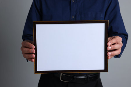 Man with diploma blank frame on light gray background, closeup. Mockup for design