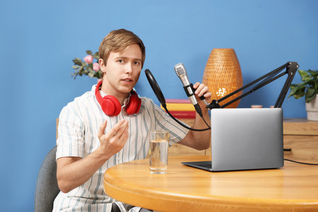 Podcast host recording talk show at wooden table indoors, view from cameraの写真素材