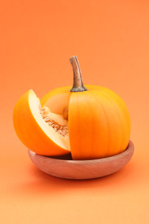 One cut ripe pumpkin on orange backgroundの写真素材