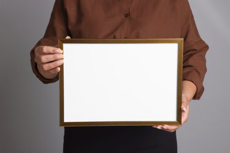 Woman with blank frame on light gray background, closeup. Mockup for designの写真素材