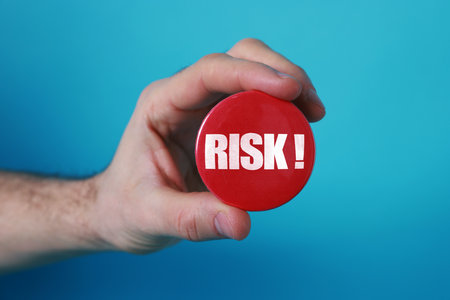 Man holding red button badge with word Risk against blue background, closeupの写真素材