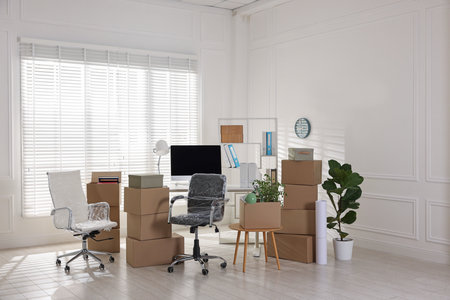 Moving day. Cardboard boxes, computer and furniture in officeの写真素材