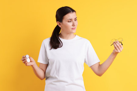 Young woman choosing between glasses and contact lensesの写真素材
