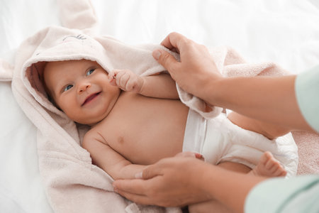 Mother covering her baby with towel after bathing on bed, closeupの写真素材