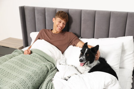 Pet friendly hotel. Man and his cute dog in bed indoorsの写真素材