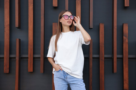 Young woman wearing blank white t-shirt near wall. Mockup for designの写真素材