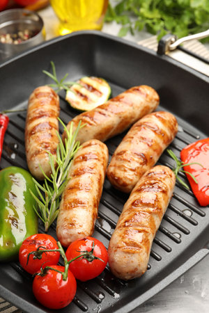 Pan with grilled sausages, vegetables and spices on table, closeupの写真素材