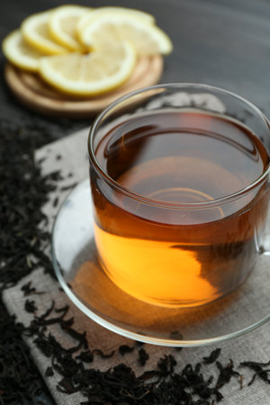 Aromatic black tea in glass cup, dried leaves and lemon on table, closeupの写真素材