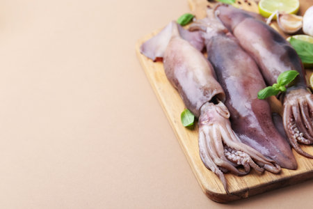 Fresh raw squids with spices on beige table, closeup. Space for textの写真素材
