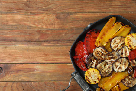 Tasty grilled vegetables in pan on wooden table, top view. Space for textの写真素材