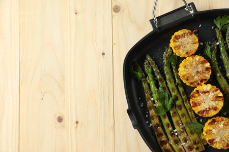 Delicious grilled vegetables with spices in pan on wooden table, top view. Space for textの写真素材
