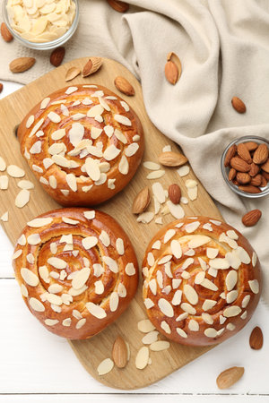Tasty roll buns with almond flakes and nuts on white wooden table, flat layの写真素材