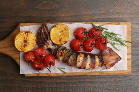 Tasty stuffed squid, rosemary, lemon and tomatoes on wooden table, top viewの写真素材