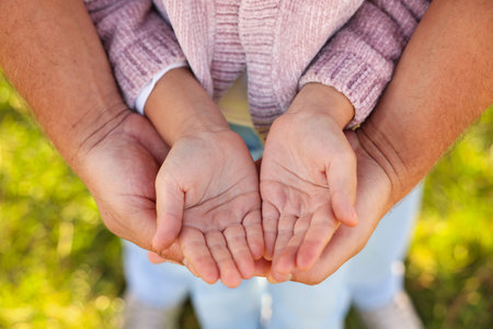 Father with his daughter holding hands outdoors, closeup. Family bonding