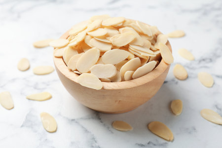 Fresh almond flakes in bowl on white marble table, closeupの写真素材