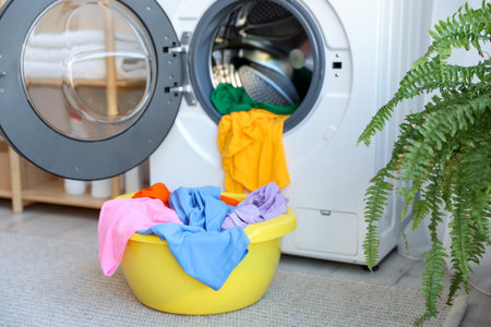 Plastic basin with laundry near washing machine in bathroom, closeupの写真素材