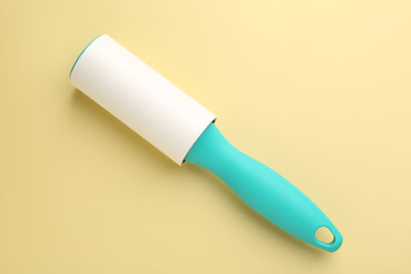 One lint roller on yellow background, top view