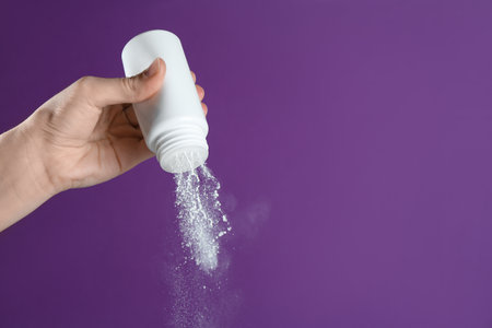 Woman with talcum powder on purple background, closeup. Space for textの写真素材