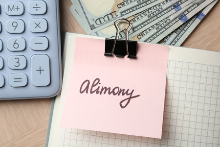 Note with word Alimony, money, notebook and calculator on wooden table, closeupの写真素材