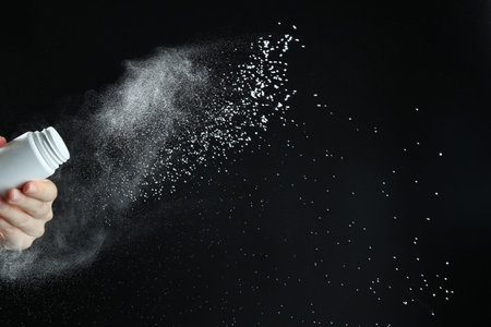 Woman with talcum powder on black background, closeup. Space for text
