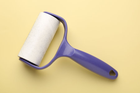 Lint roller with used sticky tape on yellow background, top viewの写真素材