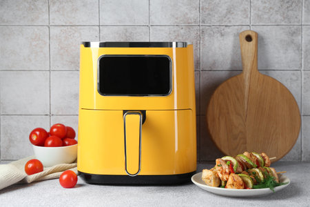 Tasty skewers with chicken, vegetables and air fryer on light gray tableの写真素材