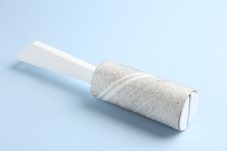 Lint roller with used sticky tape on light blue background, closeupの写真素材