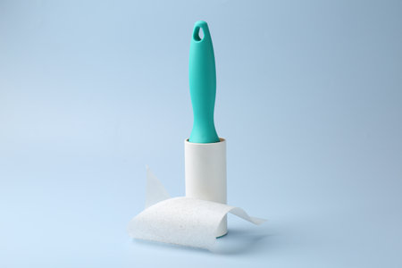 Lint roller with used sticky tape on light blue backgroundの写真素材
