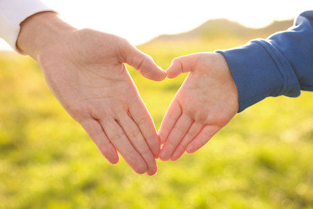 Mother making heart gesture with her son outdoors, closeup. Family bondingの写真素材