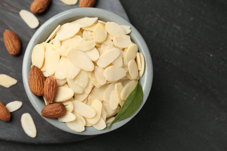 Fresh almond flakes and whole nuts on gray table, flat lay. Space for textの写真素材