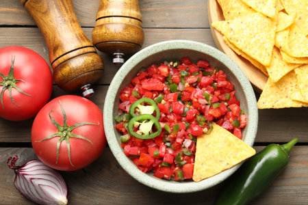 Tasty salsa with nachos and ingredients on wooden table, flat layの写真素材