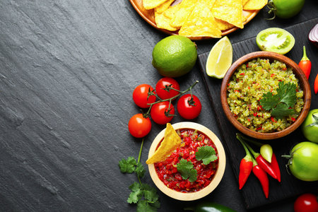 Tasty salsa in bowl and ingredients on black table, flat lay. Space for textの写真素材