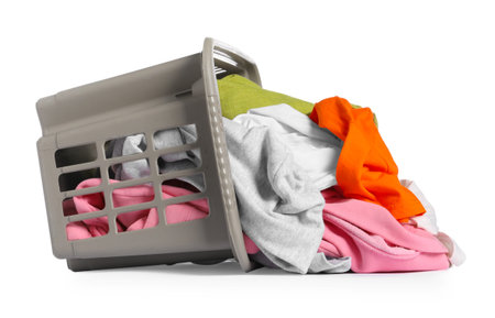Overturned laundry basket with clothes isolated on whiteの写真素材