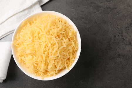 Grated cheese in bowl on gray table, top view. Space for textの写真素材