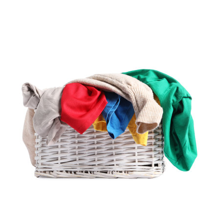 Wicker laundry basket full of colorful clothes isolated on whiteの写真素材